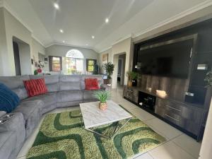 ein Wohnzimmer mit einem Sofa und einem großen Flachbild-TV in der Unterkunft Caribbean Estates Villa Caylee - Ultra-Luxurious - Rimas Interiors Designs - Private Beachfront Escape - Premium serviced for 8 Guests in Port Edward
