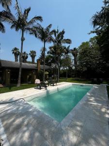 a swimming pool with palm trees and a house at La Arboleda in Corrientes