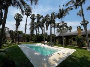 a swimming pool in front of a house with palm trees at La Quinta in Corrientes