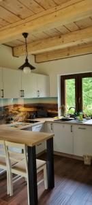 a kitchen with a table and a wooden ceiling at Domek ASPEN in Wetlina +25 photos