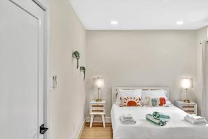 een witte slaapkamer met een bed en 2 lampen bij 1 bedroom tropical pool house in Hallandale Beach