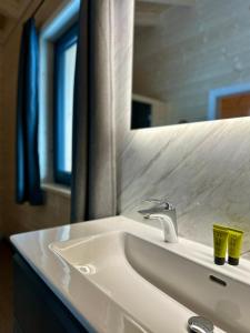 ein weißes Waschbecken mit einem Spiegel und einem Waschbecken in der Unterkunft Clofers Nature Chalets Obermöschach in Hermagor