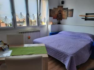a bedroom with a bed and a table and windows at Appartamento Yuki in Dervio