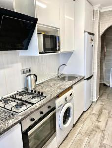 Una cocina con estufa, lavadora y secadora. en Shared apartment! Piso compartido! Общая квартира!, en Sevilla