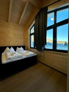 a bedroom with a bed with a large window at Clofers Nature Chalets Obermöschach in Hermagor