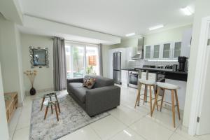 a living room with a couch and a kitchen at Hallack Du Parc Modern Living in Port Elizabeth