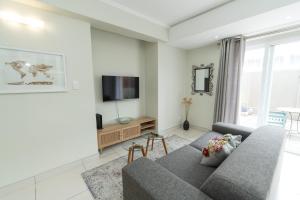 a living room with a couch and a tv at Hallack Du Parc Modern Living in Port Elizabeth