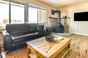 a living room with a black leather couch and a wood stove at Colorado Springs Condo with Fireplace Near Downtown in Colorado Springs