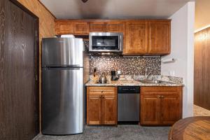 a kitchen with wooden cabinets and a stainless steel refrigerator at Studio Queen Room Ground Floor Unit 113 Bldg B in Truckee