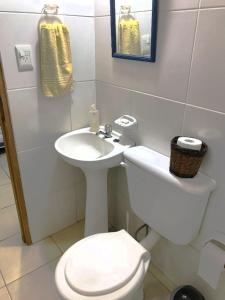 a white bathroom with a toilet and a sink at La Ofis Apart in Eldorado