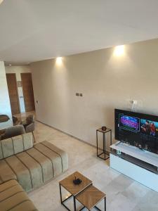 a living room with a couch and a flat screen tv at Appartement Golf City Prestigia Marrakech in Marrakesh