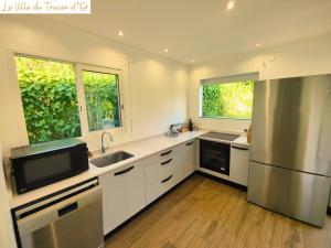 eine Küche mit weißen Schränken, einer Spüle und einem Kühlschrank in der Unterkunft La Villa du Toucan d'Or, au cœur de la Guadeloupe in Petit-Bourg