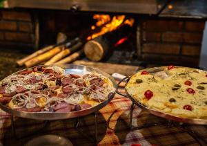 two pizzas in pans on a table next to a fire at Vale Encantado - Eco Park & Hotel in Biritiba-Mirim