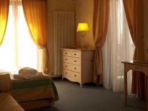 a bedroom with a bed and a dresser with a lamp on it at Du Lac Vital Mountain Hotel in Molveno