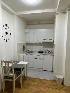 a kitchen with white cabinets and a table with chairs at Loli apartman in Kraljevo