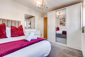 a bedroom with a large white bed with red pillows at LiveStay - Stylish 3-Bed Gem in Trendy E1 London in London