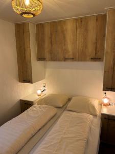 two beds in a room with two lights and cabinets at Chalet Sjaantje in Egmond aan den Hoef