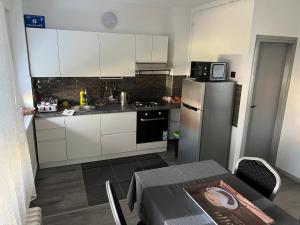 uma cozinha com armários brancos, um frigorífico e uma mesa em Apartman MOZART em Slavonski Brod