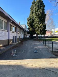 un estacionamiento junto a un edificio con un árbol en Apartman MOZART, en Slavonski Brod