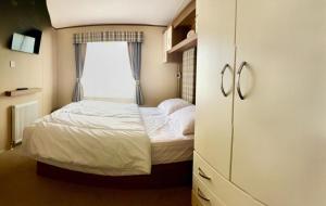 a small bedroom with a bed and a window at Warren Haven in Dawlish Warren