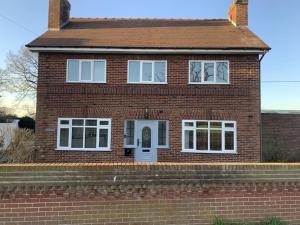 a red brick house with a white door at Wayside farmhouse stay 