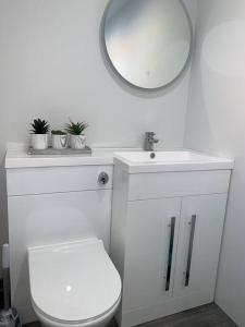 uma casa de banho branca com um WC e um espelho. em Wayside farmhouse stay 
