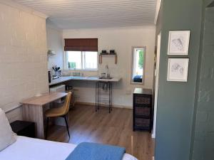 a room with a bed and a kitchen with a table at Lovely Garden Studio 2 - 10 minute walk to beach in Cape Town