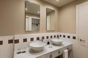 a bathroom with two sinks and two mirrors at Precise Resort El Rompido-The Hotel in El Rompido