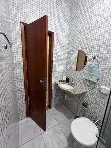 La salle de bains est pourvue de toilettes, d'un lavabo et d'un miroir. dans l'établissement Andres' Home Vila Bretas, à Governador Valadares