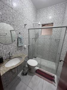 La salle de bains est pourvue de toilettes, d'un lavabo et d'une douche. dans l'établissement Andres' Home Vila Bretas, à Governador Valadares