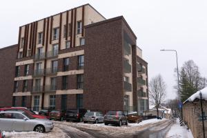 a large brick building with cars parked in a parking lot at Bossa Nova - modern 2 bedroom apartment in the center in Vilnius