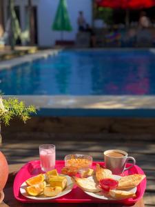 a tray of breakfast food on a table next to a pool at Point Hostel in La Pedrera