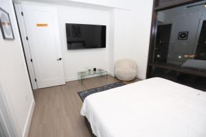 a bedroom with a white bed and a tv at Skyline Retreat Downtown HTX in Houston