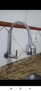 a kitchen sink with a metal faucet over a counter at Apartamento amplo in Praia Grande