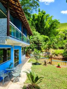 niebieski dom ze stołem i krzesłami na dziedzińcu w obiekcie Sítio do Sossego w mieście Cachoeiras de Macacu