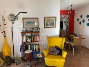 ein Wohnzimmer mit einem gelben Stuhl und einem Tisch in der Unterkunft Sunny house in Porto Santo Stefano