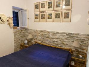 ein Schlafzimmer mit einem blauen Bett und Bildern an der Wand in der Unterkunft Sunny house in Porto Santo Stefano