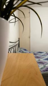 une table en bois avec un vase à côté d'un lit dans l'établissement Double room in Tooting Bec, à Londres