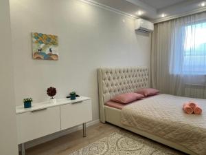 a bedroom with a bed and a table and a window at Nova Center - SQ in Astana