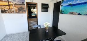 Una mesa negra con un jarrón de flores. en Apart Hotel Farol de Itapuã - Suíte com cozinha compacta à 250m da praia e farol de Itapuã en Salvador