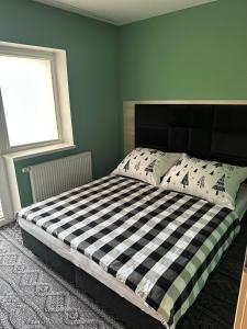 ein Schlafzimmer mit einem schwarz-weiß karierten Bett in der Unterkunft Bart Apatrments Veľká Lomnica Apartman B in Veľká Lomnica