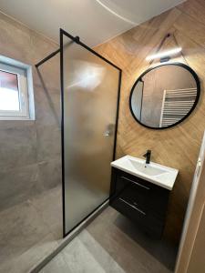 uma casa de banho com um chuveiro, um lavatório e um espelho. em Bart Apatrments Veľká Lomnica Apartman B em Veľká Lomnica