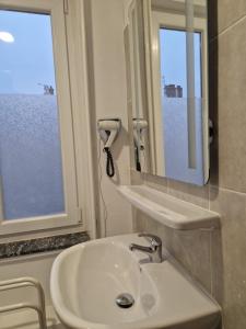 un bagno con lavandino, specchio e finestra di Hotel de l'Academie a Nancy