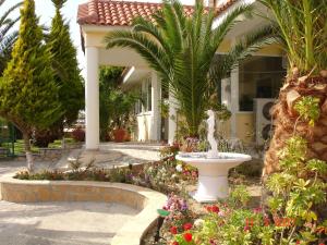 a fountain in a garden in front of a house at Metaxa Hotel in Kalamaki