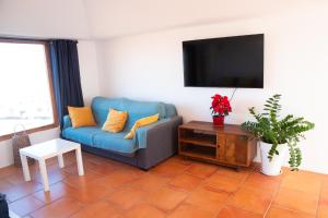 a living room with a blue couch and a flat screen tv at Castillo de Villaverde in Villaverde