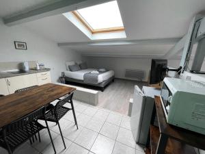 a room with a bed and a kitchen with a table at Hôtel Paris Madrid avec Piscine et restauration in Lesperon