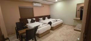 a hotel room with two beds and a table at Nebo Suites in Visakhapatnam