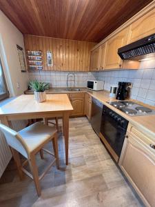Una cocina con armarios de madera, una mesa y un fregadero. en Ferienhaus Eisfelder Blick, en Eisfeld