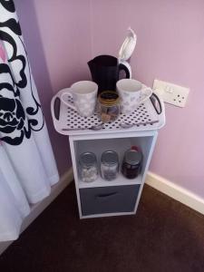 a small white shelf with jars and cups on it at Twin room in Prescot Homestay in Prescot