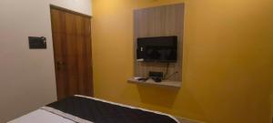 a room with a television on a yellow wall at Nebo Suites in Visakhapatnam